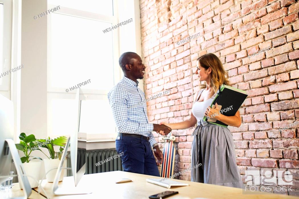 Stock Photo: Two colleagues shaking hands in office.