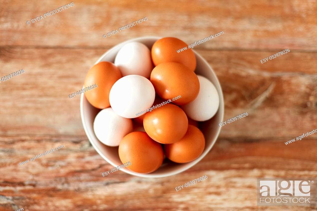 Stock Photo: close up of eggs in ceramic bowl on wooden table.