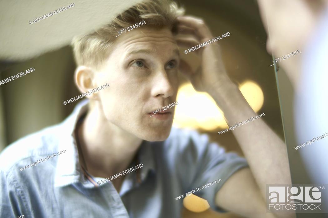 Stock Photo: young man checking his appearance in mirror.