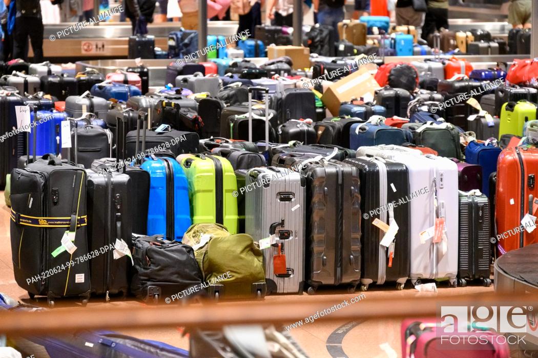 Stock Photo: 23 June 2022, Hamburg: Numerous suitcases are stored in the baggage claim area. Hundreds of suitcases, bags and baby carriages are still piled up in the baggage.