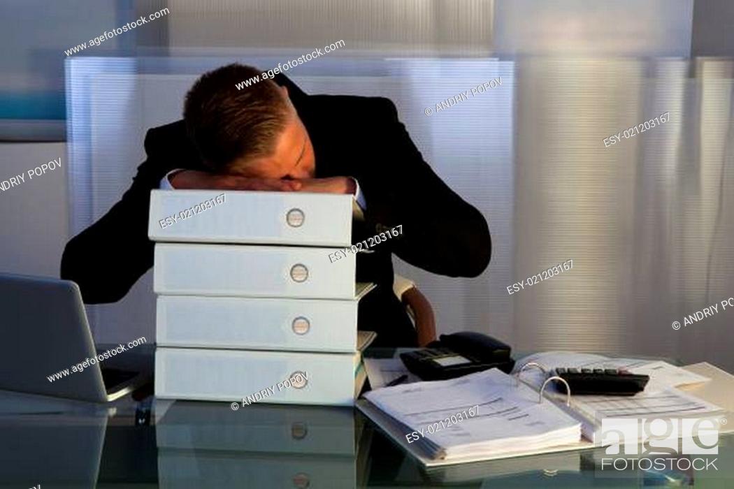 Stock Photo: Exhausted businessman sleeping an a stack of files.