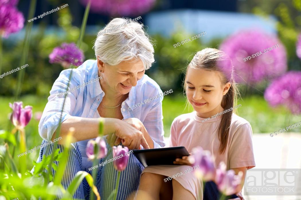 Stock Photo: grandmother and girl with tablet pc at garden.
