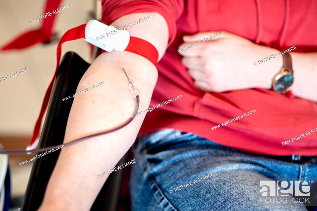 Stock Photo: PRODUCTION - 06 May 2021, Lower Saxony, Emstek: Blood runs from a donor's arm through a needle into a bag during a blood donation at the NSTOB blood donation.