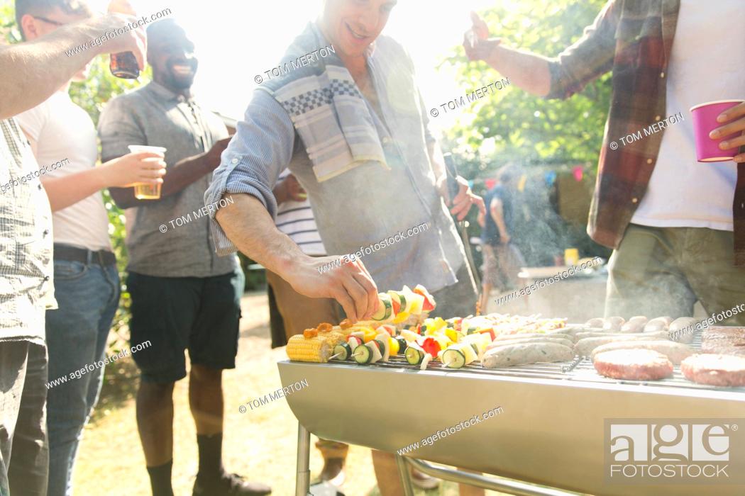 Stock Photo: Male friends barbecuing in back yard.