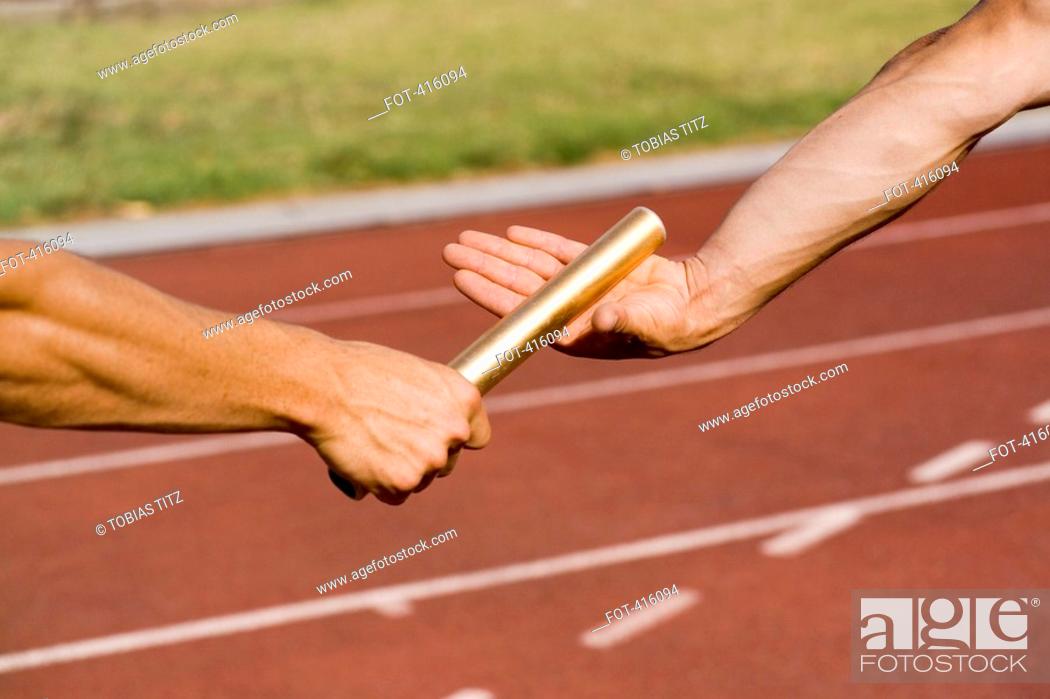 Stock Photo: Two athletes exchanging a baton during a relay race.