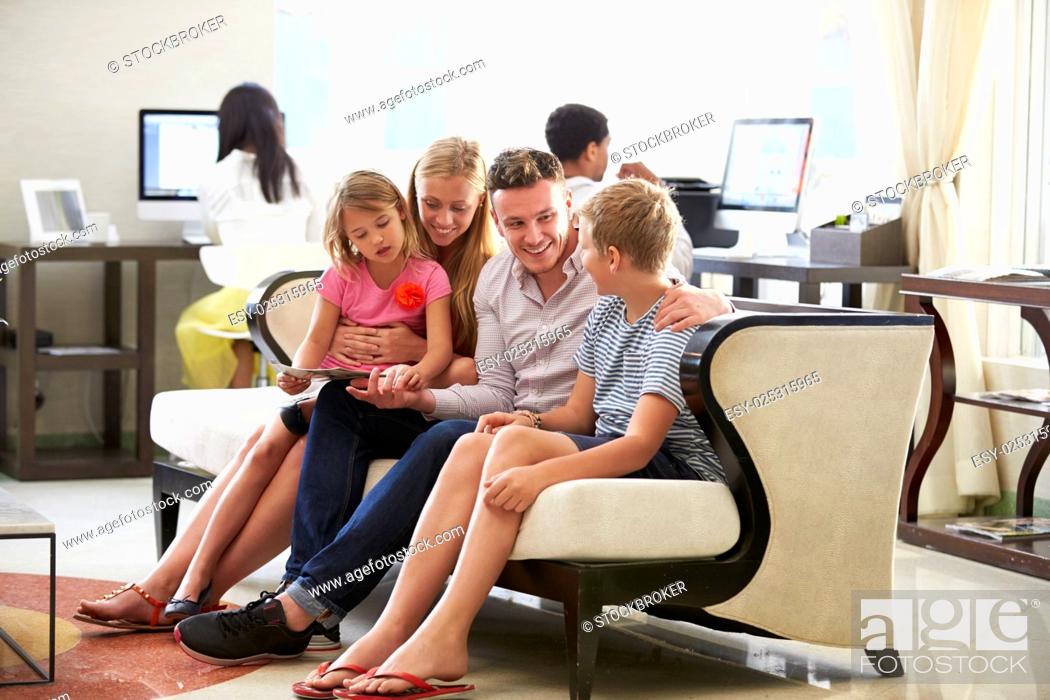 Stock Photo: Family In Hotel Lobby Looking At Digital Tablet.
