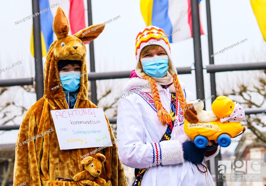 Stock Photo: 15 February 2021, Rhineland-Palatinate, Mainz: Antonia (l), dressed in a kangaroo costume, and Eva, dressed as an Inuit, stand in front of the carnival flags on.