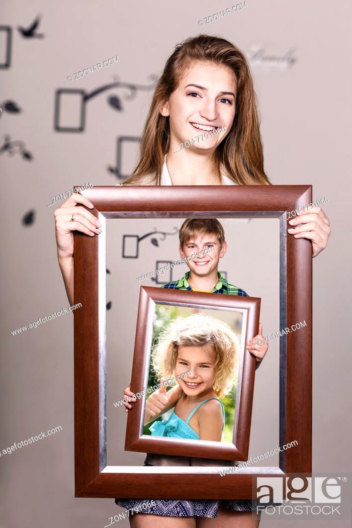 Stock Photo: Happy adult sister holding portrait with her family each is located inside their own frame.