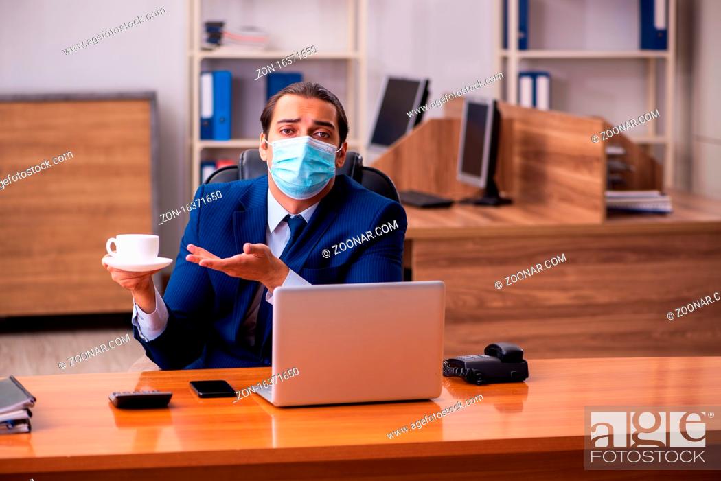 Stock Photo: Young employee working in the office wearing mask.