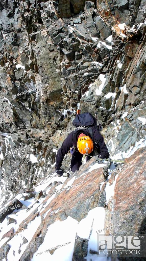 Stock Photo: A male mountain climber in a steep rock and ice couloir on his way to a high alpine summit.