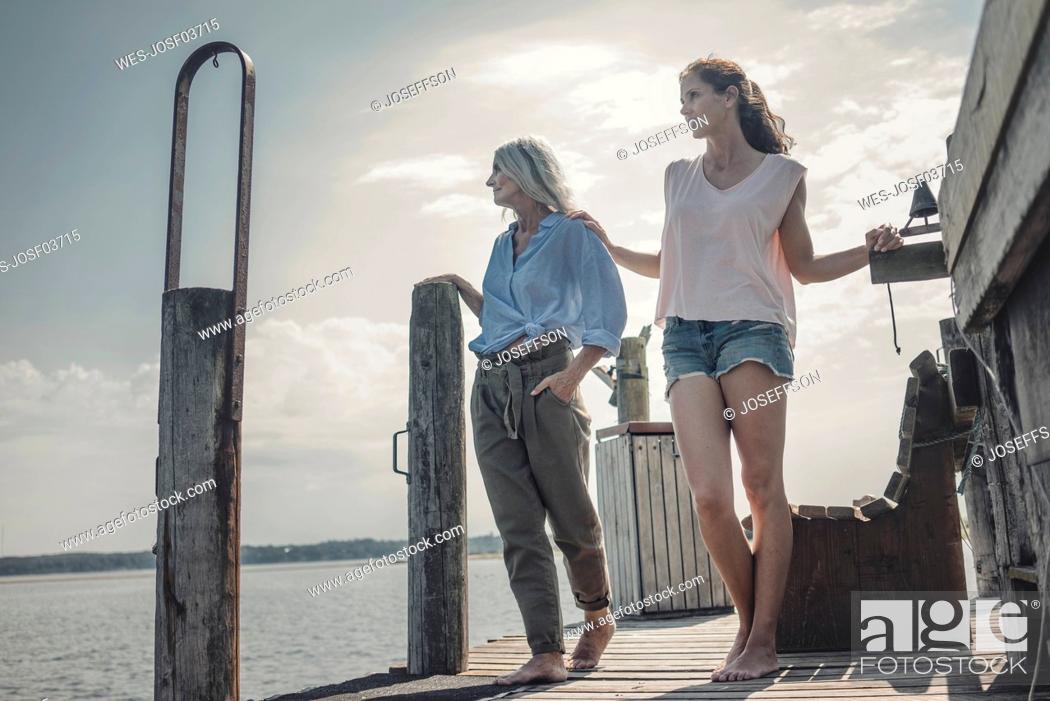Stock Photo: Mother and daughter standing on jetty, spending a day at the sea.