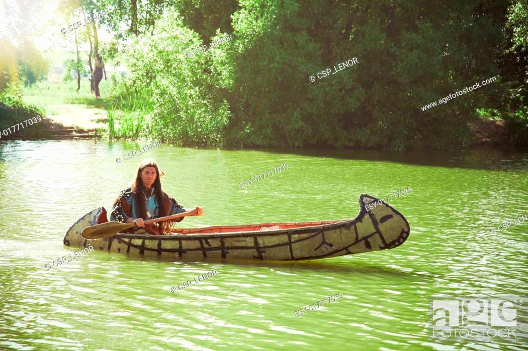 Stock Photo: North American Indian floats down the river on a canoe.