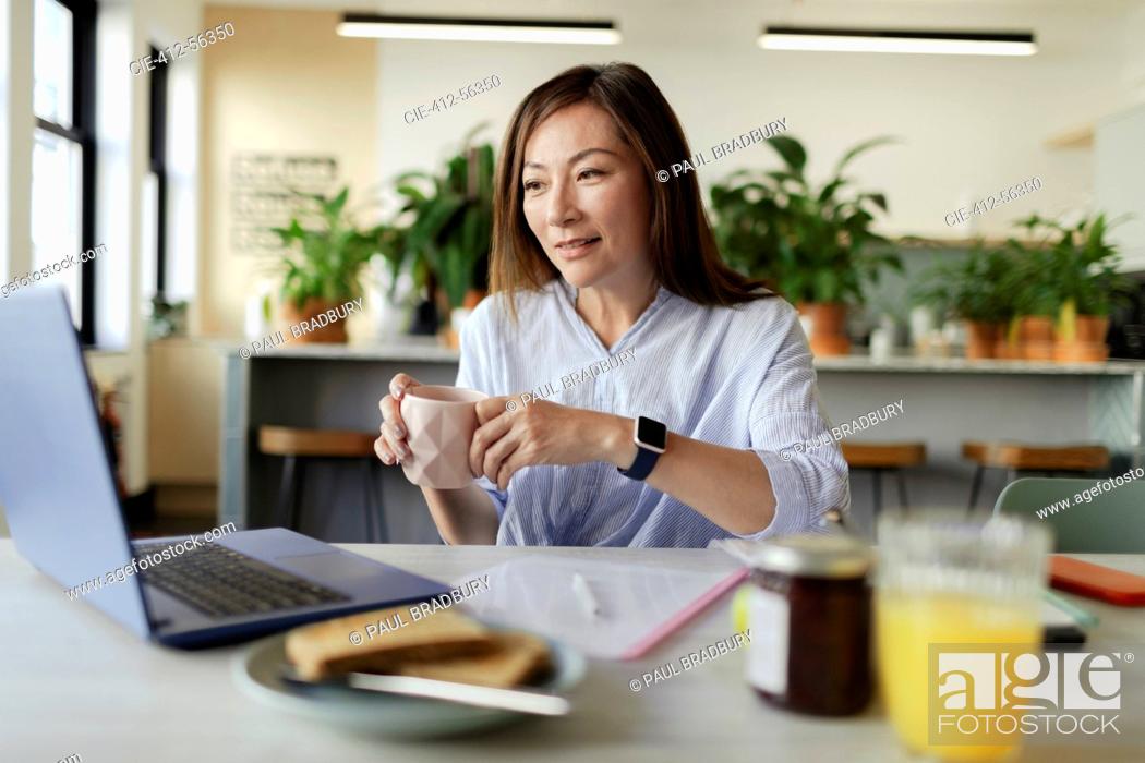 Stock Photo: Businesswoman drinking coffee at laptop in morning office.