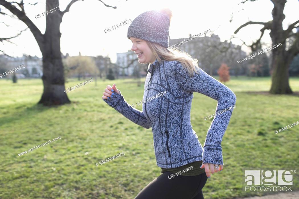 Stock Photo: Smiling female runner running in sunny park.