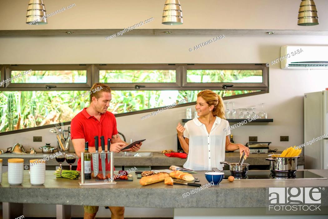 Stock Photo: Couple preparing food and using digital tablet in kitchen.