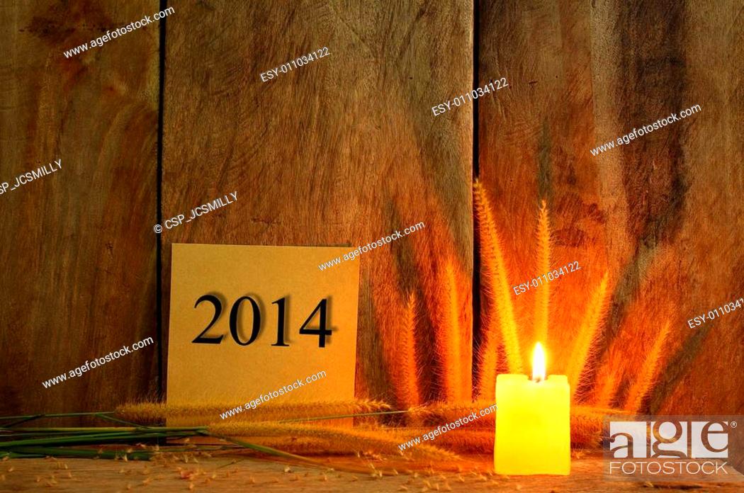 Stock Photo: Still life with 2014 wrote on notepad and candle light on wooden background.