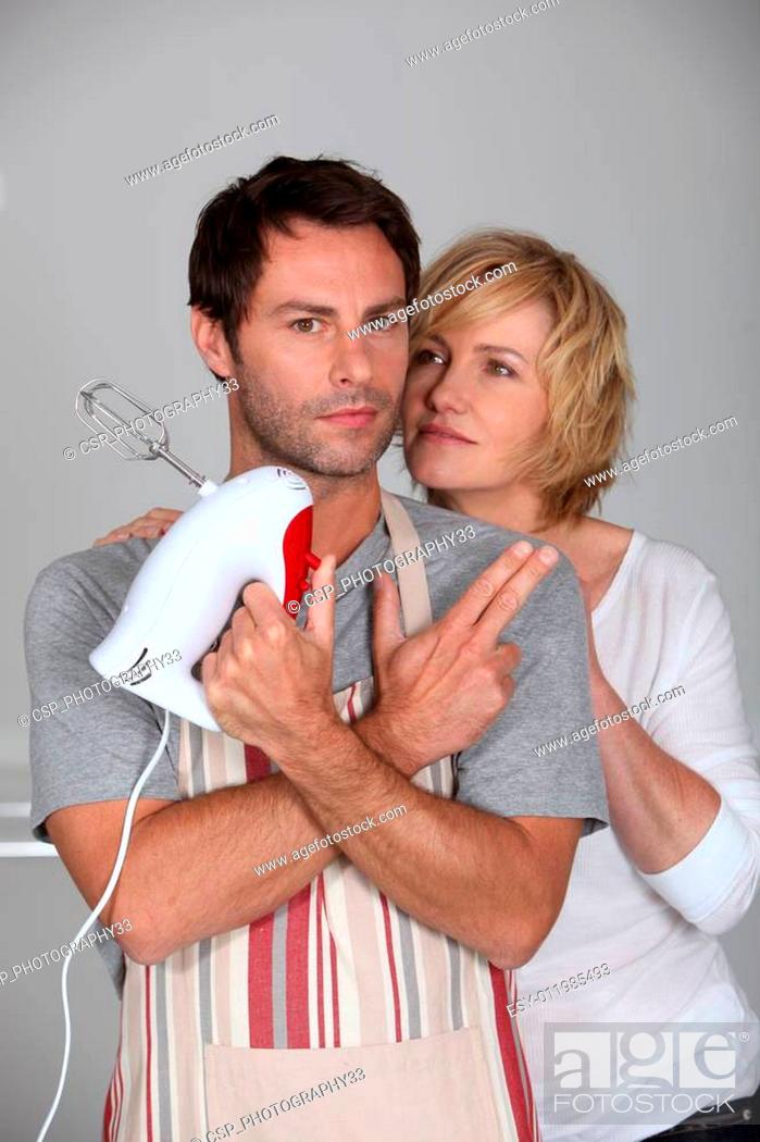 Stock Photo: man wearing apron with hand mixer and wife.
