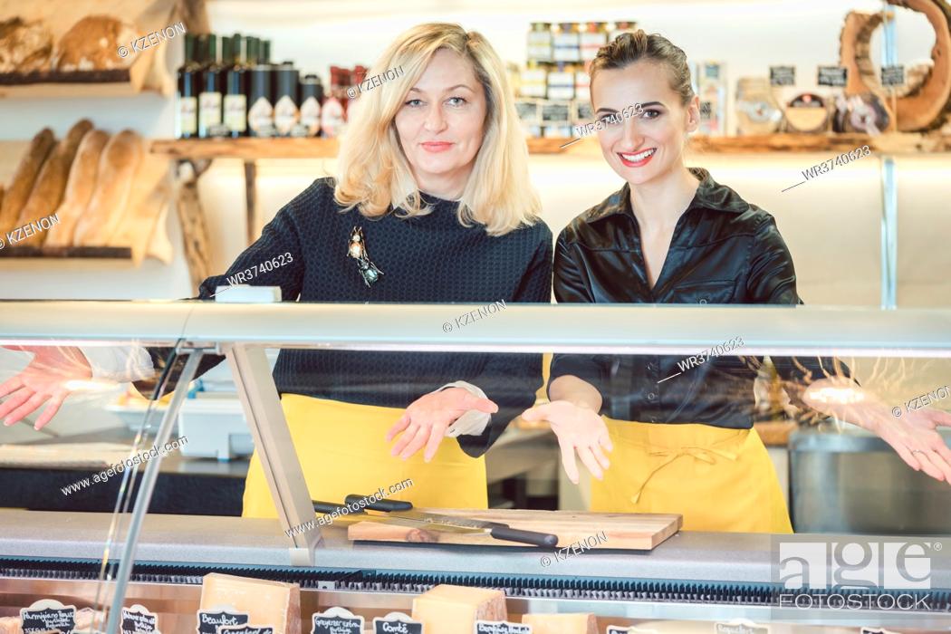 Stock Photo: Two friendly salesladies at the cheese counter offering their goods.