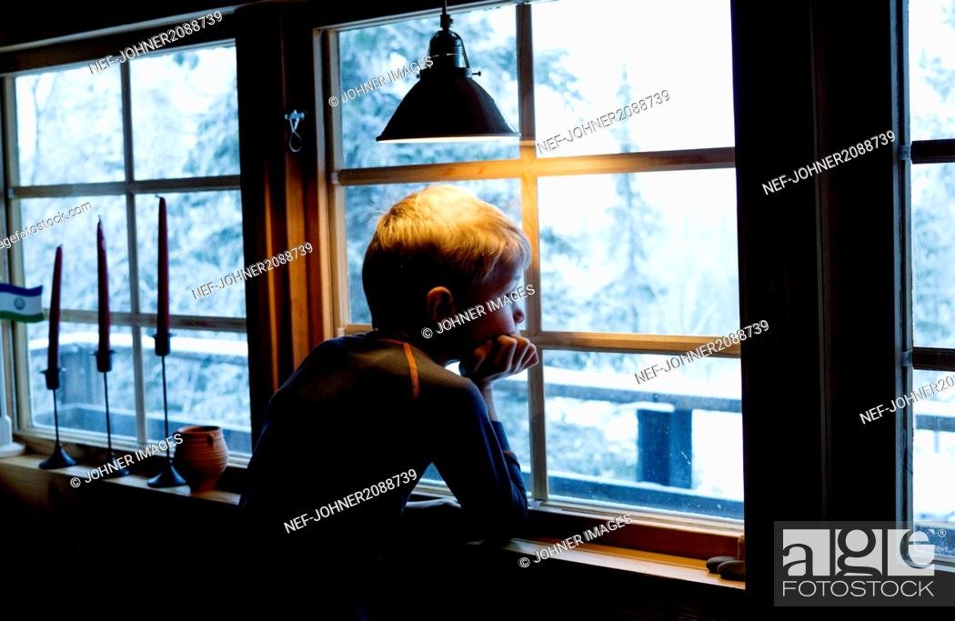 Stock Photo: Boy looking out of a window.