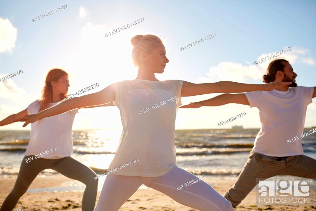 Stock Photo: fitness, sport, yoga and healthy lifestyle concept - group of people making warrior pose on beach.