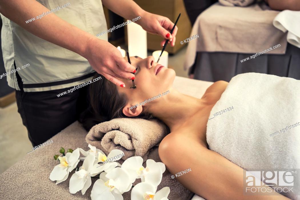 Stock Photo: Relaxed woman lying down on massage bed during facial treatment at Asian spa and wellness center.