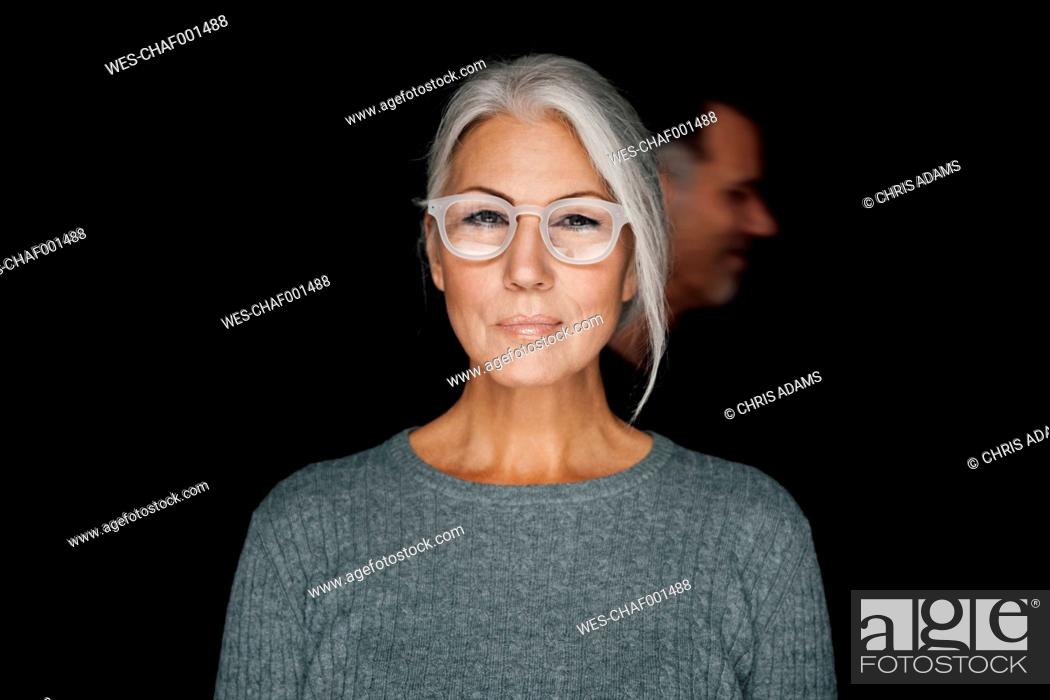 Stock Photo: Portrait of smirking woman wearing glasses in front of black background.