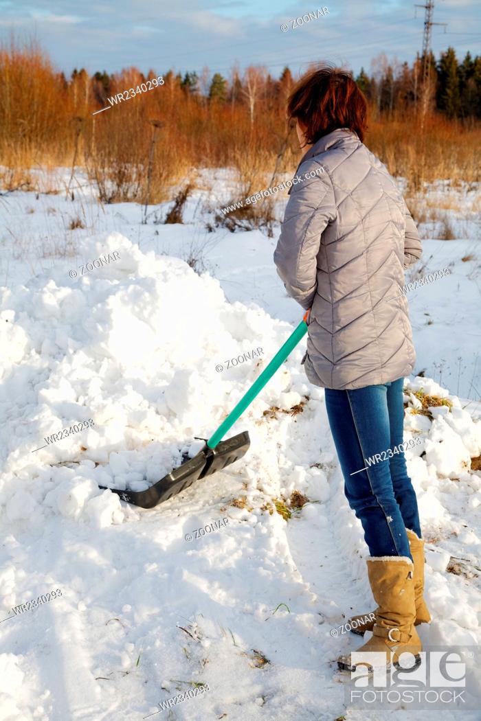 Stock Photo: The woman cleans snow a shovel.