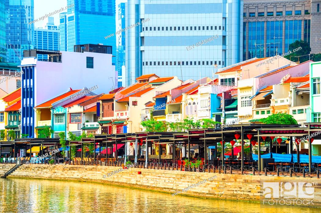 Stock Photo: Cityscape with colorful bars, restaurants and stores by the Singapore River along Boat Quay, skyscrapers of modern architecture in background.