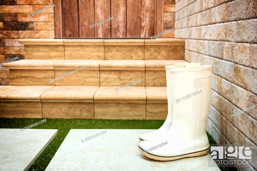 Stock Photo: Rain wet rubber boots near porch door. Rain autumn and winter concept.