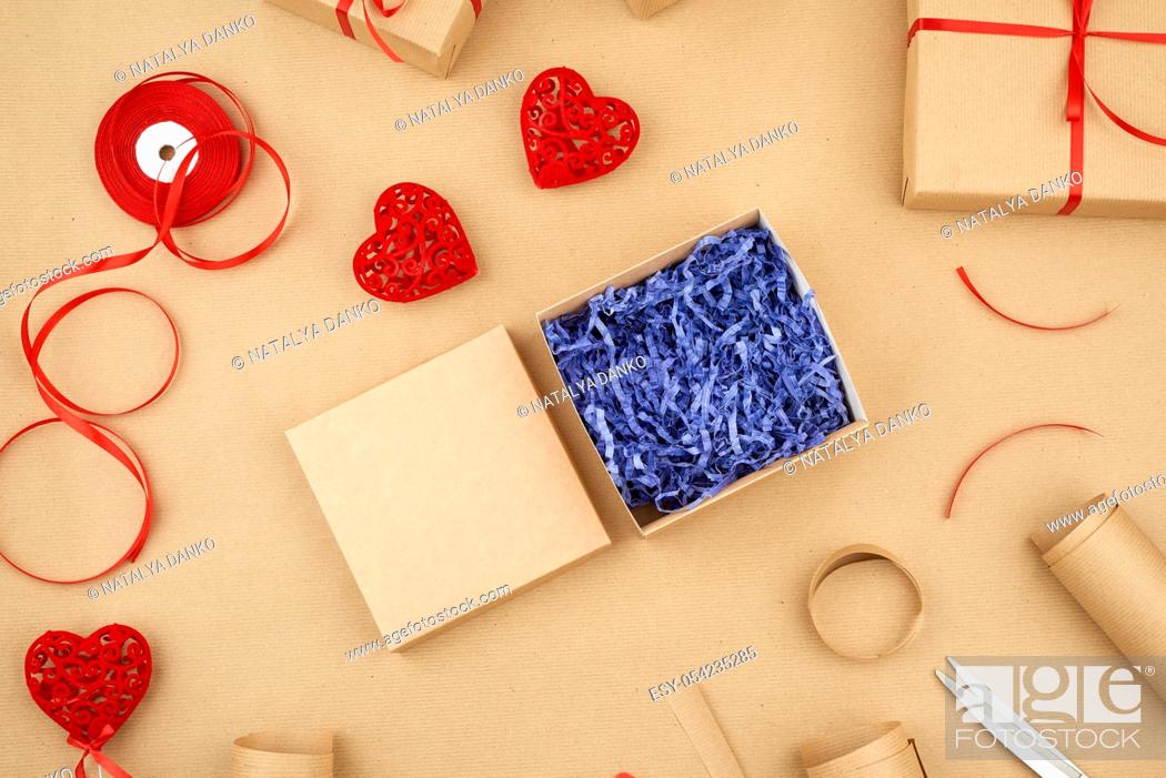 Stock Photo: brown kraft paper, packed gift boxes and tied with a red ribbon, red heart, set of items for making gifts. Package design, top view.