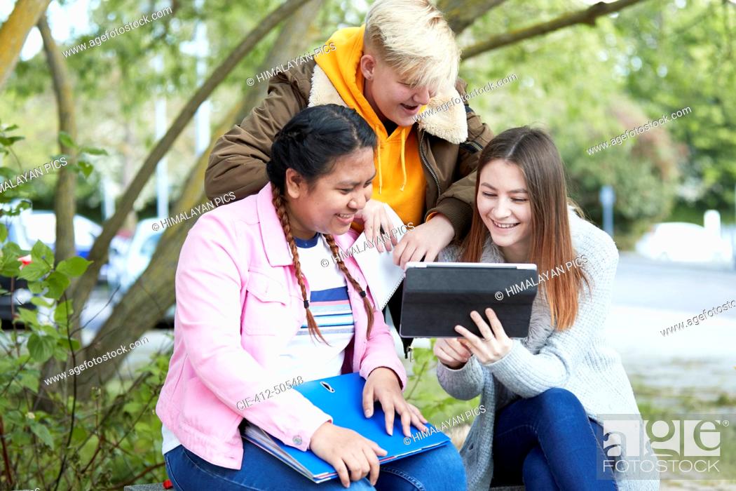 Stock Photo: College students with digital tablet studying in park.