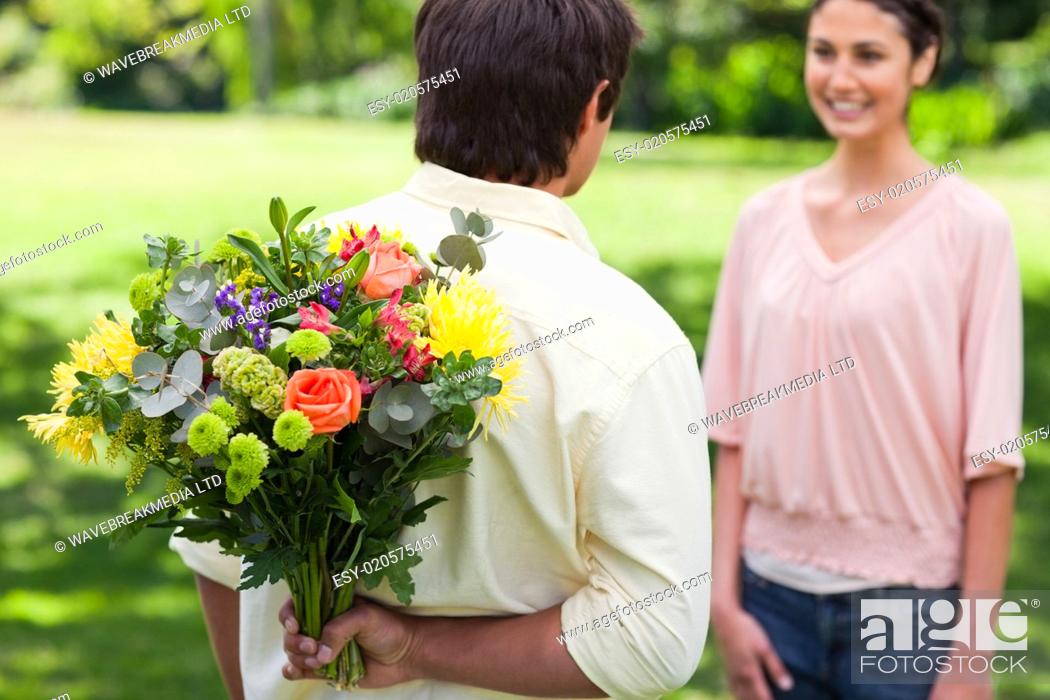 Stock Photo: Man about to present a bouquet of flowers to his friend.