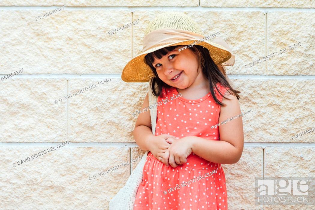 Stock Photo: Portrait of a little black-haired girl smiling with summer dress, hat and bag.