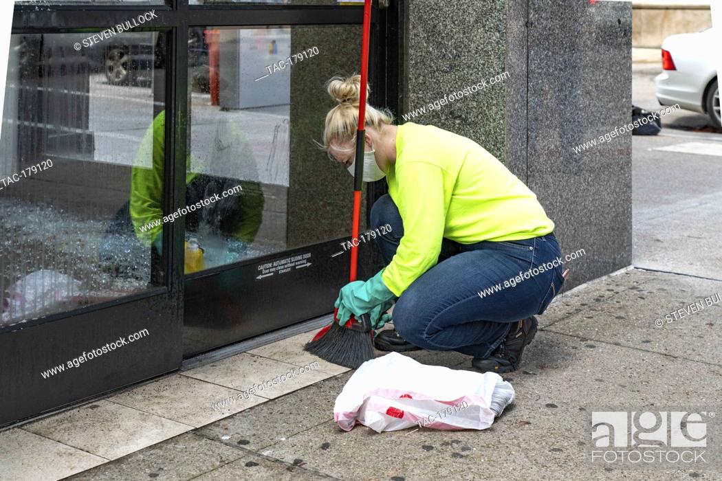 Stock Photo: A worker cleans up broken glass at the doorway of CVS Pharmacy at 4th St and Chestnut on May 30, 2020 in Louisville, Kentucky.