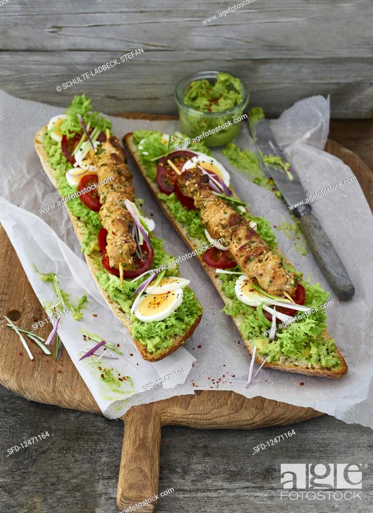 Stock Photo: Chicken kebabs on ciabatta with an avocado dip, lollo bionda lettuce, tomatoes and hard-boiled eggs.