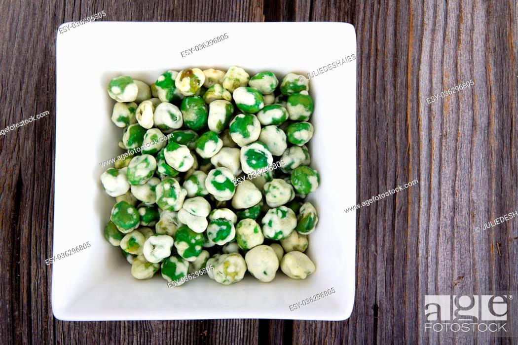 Photo de stock: Wasabi coated peas on a square bowl over wood table.