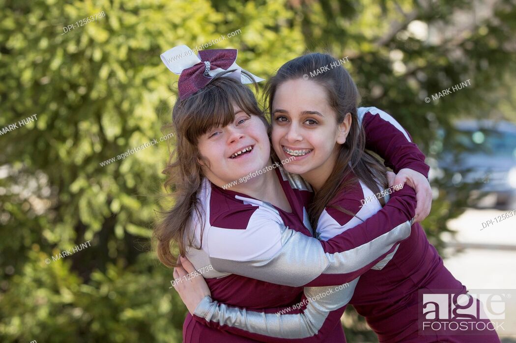 Stock Photo: Portrait of two cheerleaders hugging each other, one with Down Syndrome.