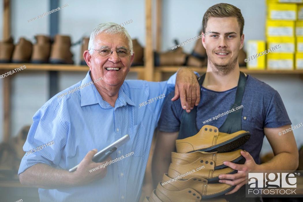 Stock Photo: Portrait of smiling senior man and young man holding shoes.