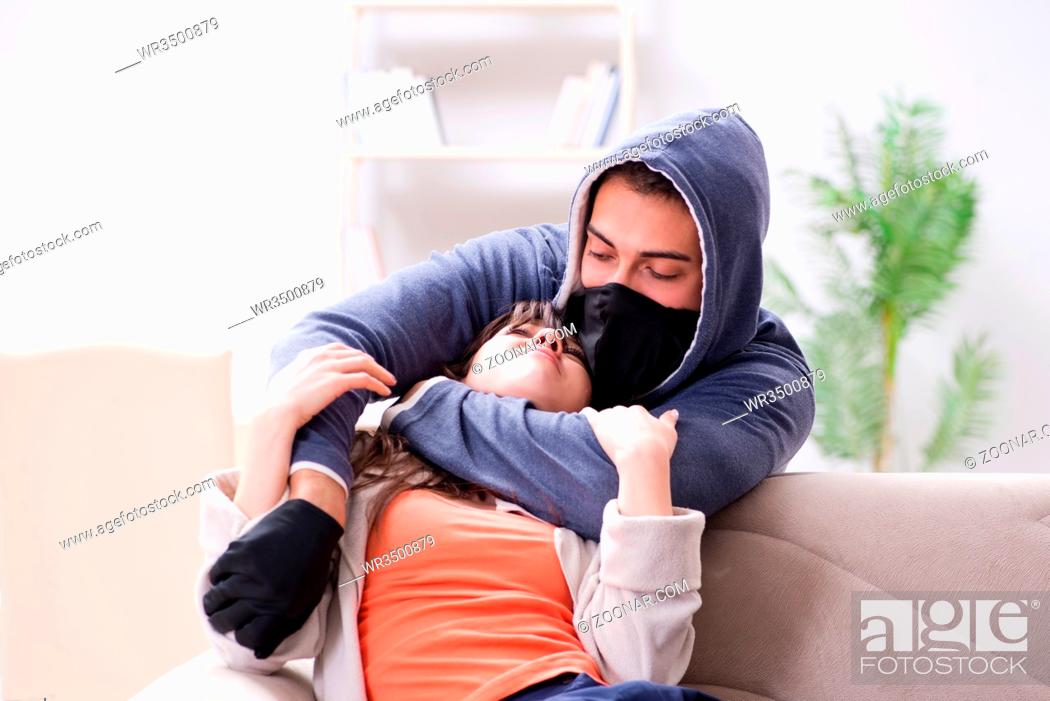 Stock Photo: Armed man assaulting young woman at home.