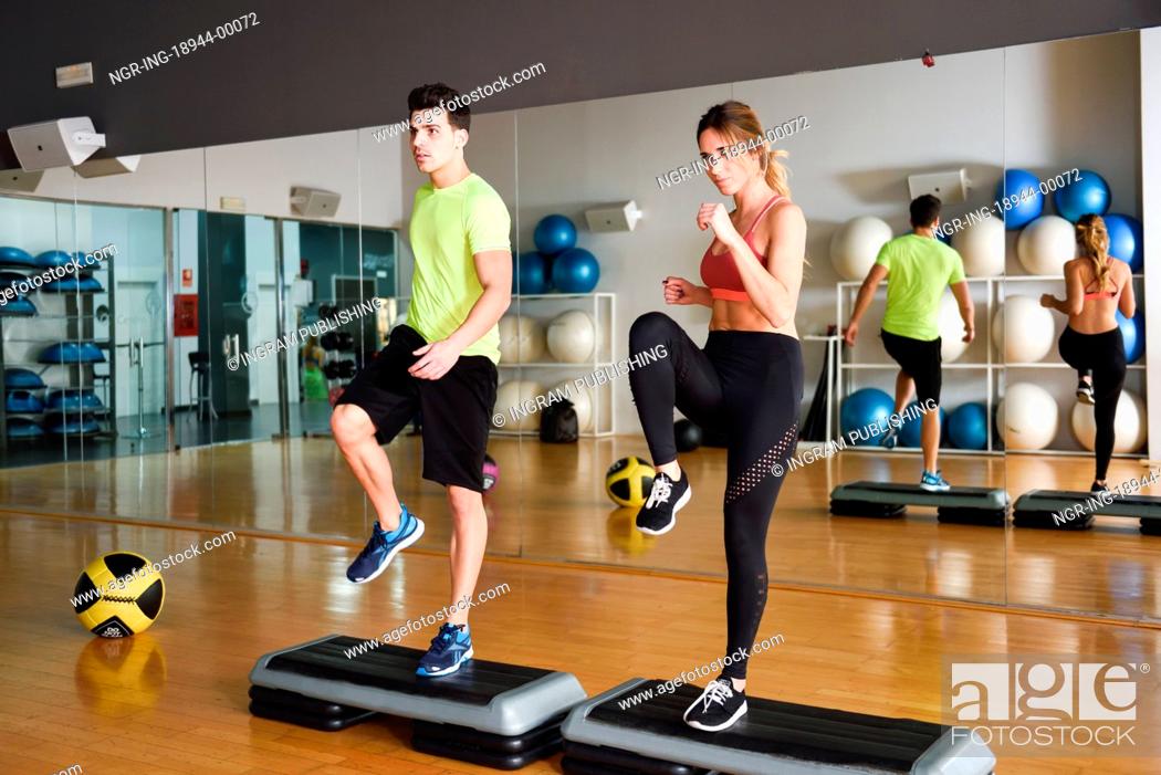Stock Photo: Two people working out with steppers in gym. Man and woman wearing sportswear clothes.