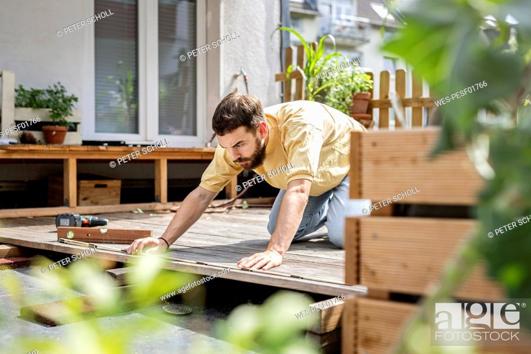 Stock Photo: Young handyman building wood terrace in front of his home.