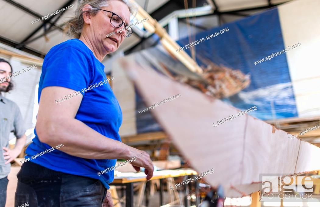 Stock Photo: 19 May 2022, Mecklenburg-Western Pomerania, Peenemünde: Boat builder Ursula Latus checks the assembly work on a two-seater in spearwood construction at the boat.