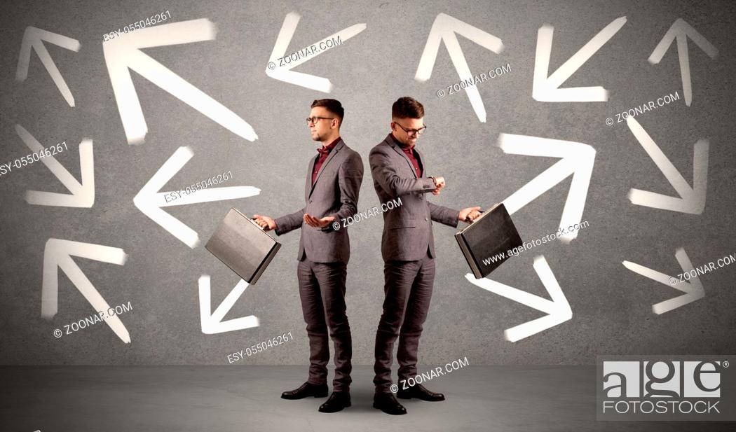 Stock Photo: Young conflicted businessman choosing between two directions with arrows around him.