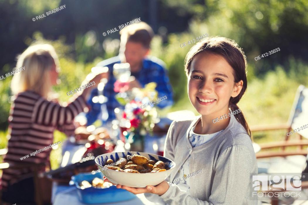 Stock Photo: Portrait smiling girl serving food at sunny garden party patio table.