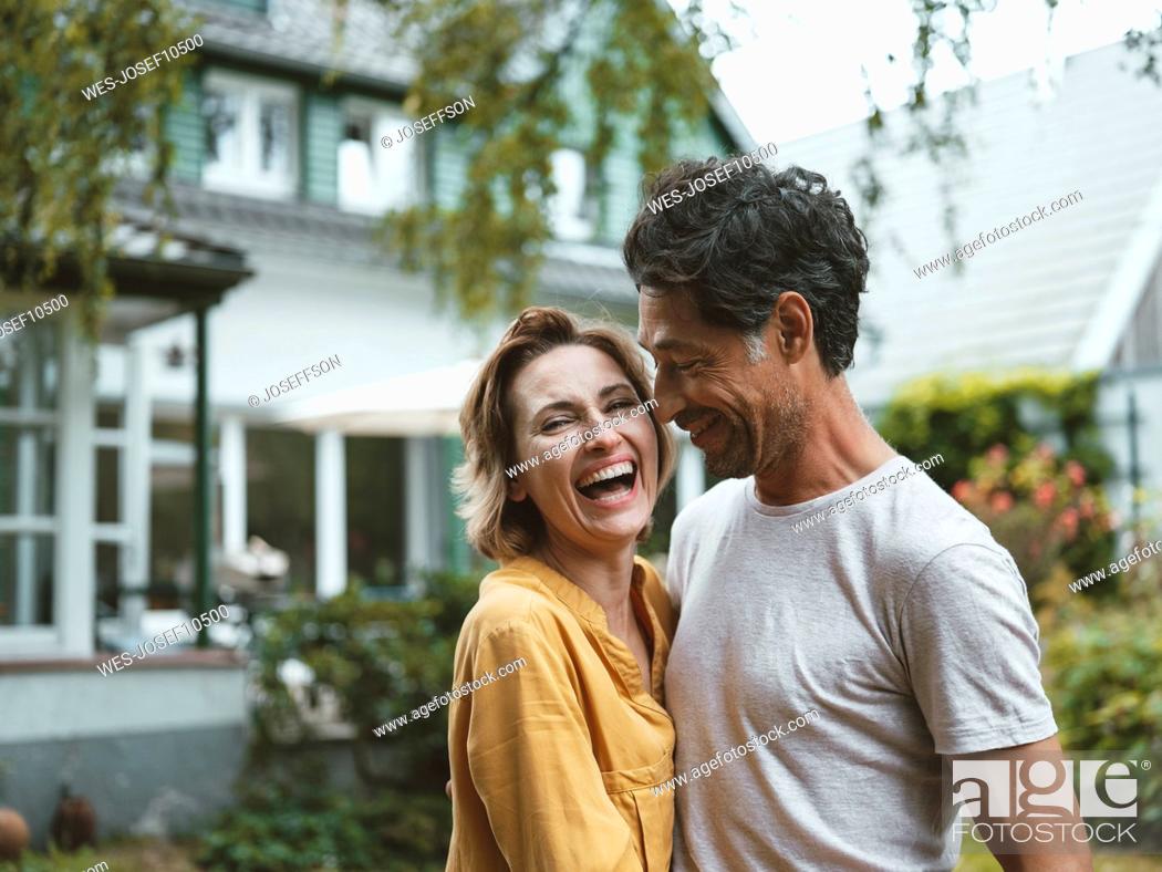 Imagen: Cheerful mature woman with man standing in front of house.