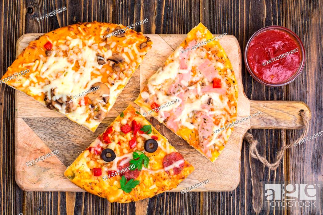 Stock Photo: Three pieces of different pizzas on a wooden. Studio Photo.