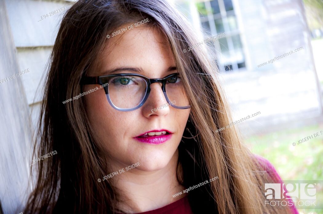 Stock Photo: A casual portrait of a 26 year old woman with long brown hair and big glasses, outdoors.