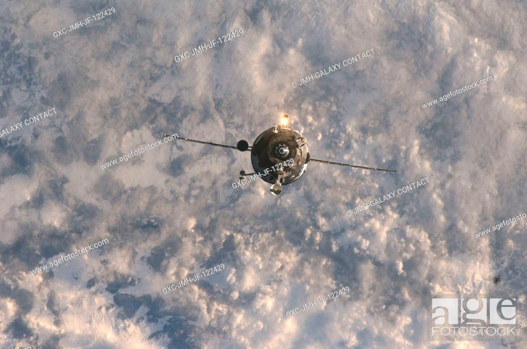 Stock Photo: Backdropped by a blanket of clouds, an unpiloted Progress supply vehicle approaches the International Space Station, bringing more than two tons of food.
