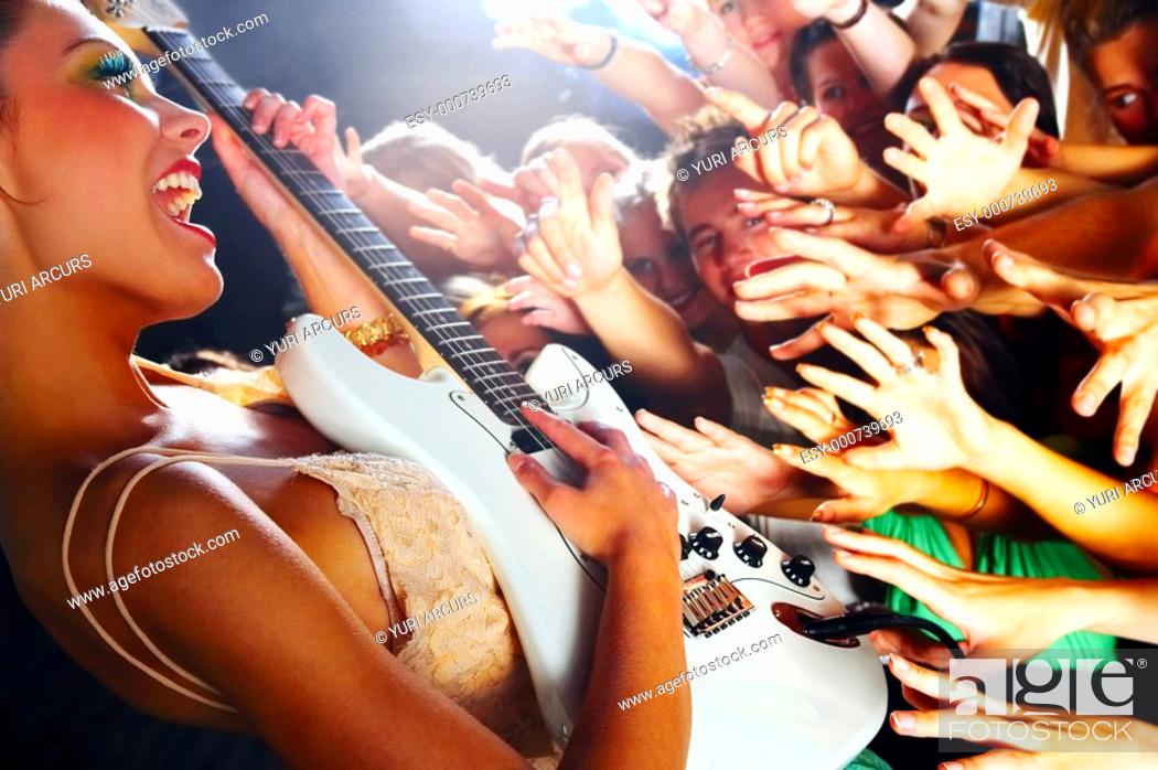 Stock Photo: A beautiful guitarist playing for her adoring fans Attention buyers: These pictures are not perfectly focused and will display some degree of noise in the.