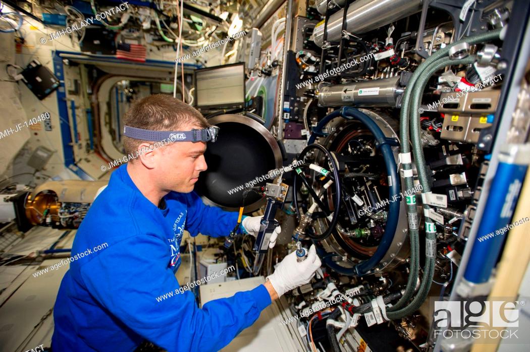 Stock Photo: NASA astronaut Reid Wiseman, Expedition 40 flight engineer, performs routine in-flight maintenance on the Multi-user Drop Combustion Apparatus (MDCA) inside the.